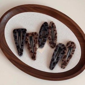 Detailed view of six leopard print plush hair clips in grey and brown tones