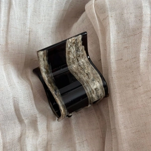 Detailed view of French-style black acetate hair claw with marble texture on fabric
