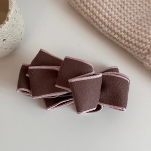 Close-up of brown suede banana clip with pink stitching and multilayered bow design