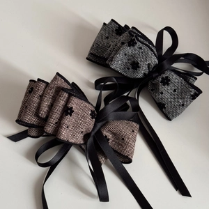 Detailed texture of tweed fabric bows with small flowers and elegant long satin ribbons