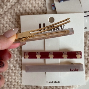 Dettaglio di tre fermagli per capelli con motivo a orso e scritta Lucky su carta