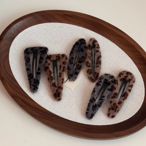 Close-up of leopard print plush hair clips in oval and triangle shapes on a wood tray