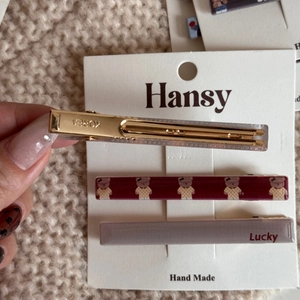 Dettaglio di tre fermagli per capelli decorativi con stampa orsetto e incisione Lucky