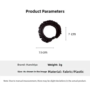 Detail showing 7.5x7cm black ruffled hair tie made of lightweight fabric and plastic