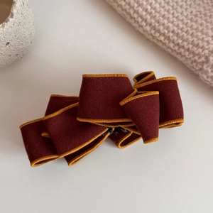 Close-up of wine red suede bow banana clip with golden edge and sturdy black base