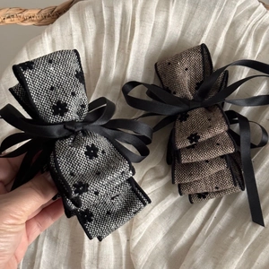 Detail of tweed bow hair clip with floral patterns and flowing ribbons for women