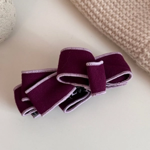 Close-up of a double-layered faux suede bow hair clip in deep purple with fine edge detail