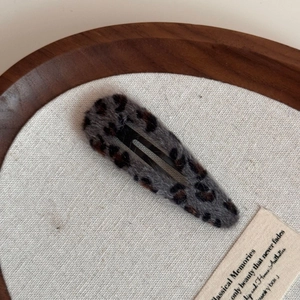 Detail of plush leopard print hair clip showing soft faux fur texture on a wooden tray