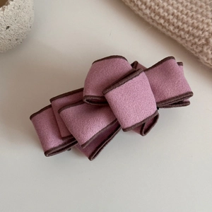 Detail showing layers of pink faux suede bow hair clip with dark stitching accents