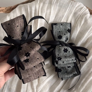 Detailed close-up of velvet floral layered bow hair clips in brown and grey fabric