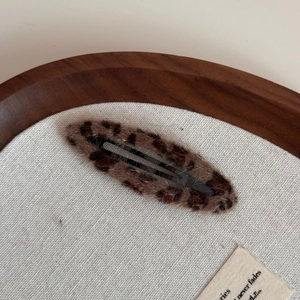 Close-up of leopard print plush hair clip with soft texture on a wooden tray
