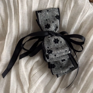 Detail of tweed bow hair clip with embroidered flowers and long satin ribbons