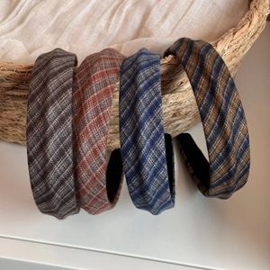 Close-up of four plaid fabric headbands in autumn colors showing tweed texture and wide design