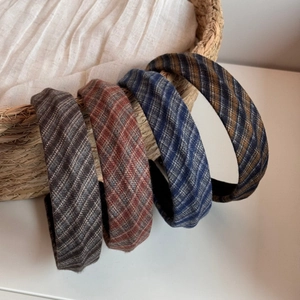 Close-up of four plaid fabric headbands in retro colors hanging on a woven basket