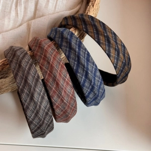 Detail of four retro plaid fabric headbands in brown, red, blue, and navy tweed textures