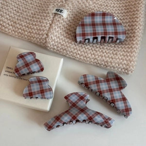 Macro detail of retro red and blue checkered acetate hair claws set on a cozy knit fabric