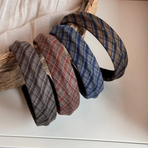Detail of four vintage plaid headbands in various colors hanging on a straw basket
