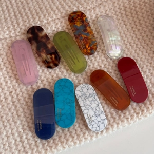 Flat lay of diverse oval acetate hair clips in marble and tortoiseshell patterns