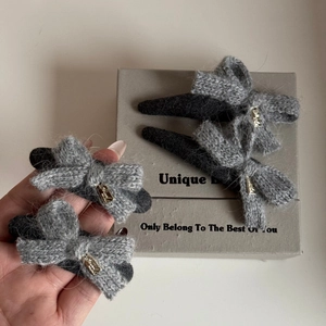 Detailed macro view of soft knit grey bow hair clips with premium golden metal accents