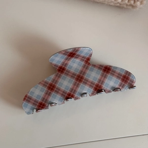 Detail view of red and blue plaid acetate hair claw clip on beige knit background
