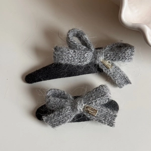 Detail shot of grey knitted bow hair clips with soft wool texture and golden metal tags