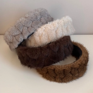 Detailed macro view of four plush braided headbands in grey, beige, brown and khaki colors