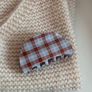 Close-up of red and blue checkered acetate hair claw clip on beige knitted fabric