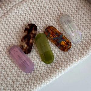 Detail of five-piece oval acetate hair clips in assorted colors on soft knit fabric