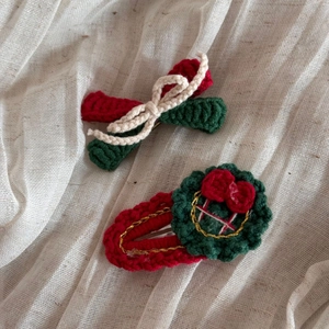 Détail de barrettes de Noël tricotées main avec nœuds et motifs floraux rouges et verts