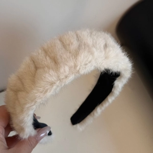 Close-up of a thick cream plush headband showing fuzzy faux mink fur texture and black lining