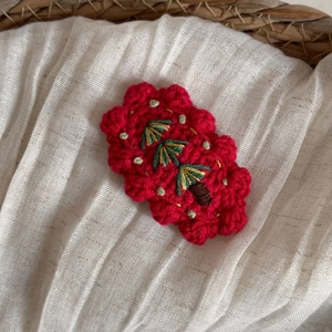 Gros plan détaillé d'une pince à cheveux rouge tricotée avec broderie de sapin de Noël