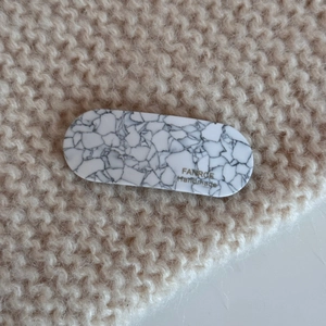 Close-up of black and white marble acetate hair clip on beige knit background