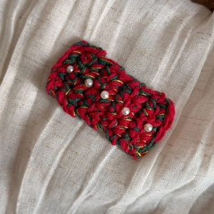 Détail de la pince à cheveux de Noël en tricot avec perles rouges et vertes