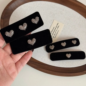 Vue détaillée de barrettes en velours noir ornées de motifs de cœurs en strass argentés