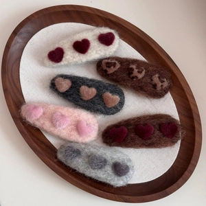 Detail view of colorful heart and cat paw plush hair clips on a wooden tray