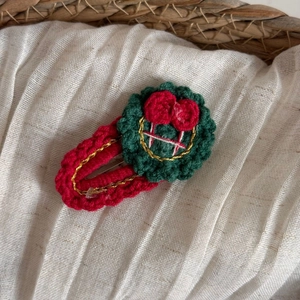 Vue détaillée de la pince à cheveux couronne de Noël tricotée à la main avec petits nœuds rouges