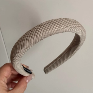 Détail d'un serre-tête rembourré champagne avec texture sergé et embouts noirs