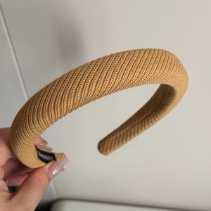 Détail du serre-tête en tricot montrant la texture sergé jaune et l'étiquette