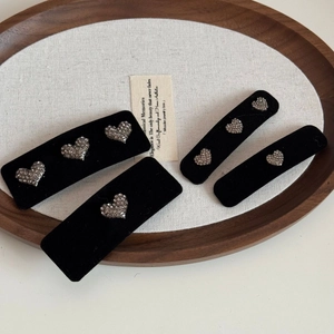 Détail de quatre barrettes en velours avec motifs de cœurs en strass sur un plateau