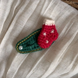Détail de la pince à cheveux crochetée à la main en forme de chaussette de Noël avec perle