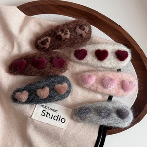 Close-up of plush heart hair clips with soft wool texture for autumn and winter styling
