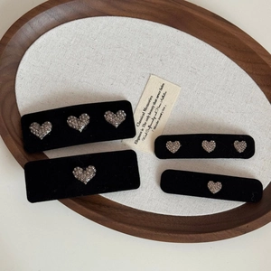 Détail de barrettes en velours noir avec cœurs en strass et base rectangulaire