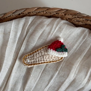 Détail d'une pince à cheveux bonnet de Noël en tricot avec bordure dorée et perle sur tissu