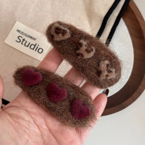 Detailed close-up of plush heart hair clips featuring leopard print and burgundy faux fur