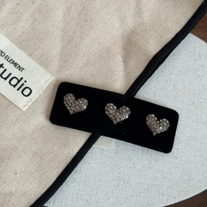 Gros plan de trois barrettes à strass en forme de cœur sur une carte en velours noir