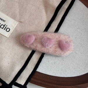 Close-up of a light pink plush heart hair clip with three soft faux fur hearts