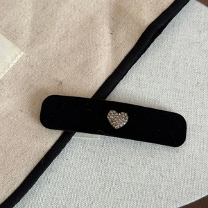 Gros plan détaillé sur une pince à cheveux en velours noir avec un décor cœur en strass