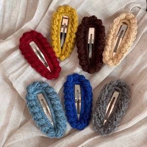 Set of seven handmade knit wool hair clips in various candy colors on beige linen background