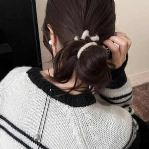Élastique à cheveux en tricot crème et collier montrés sur une coiffure en chignon