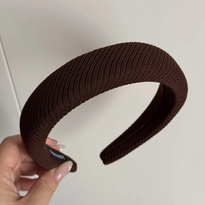 Détail du serre-tête en tricot marron café montrant la texture douce et l'étiquette faite main